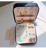 Estuche negro abierto con pulsera, aretes y collares junto a separadores desmontables.