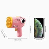 Pistola de burbujas rosada con forma de dinosaurio, vista de perfil, con medidas dibujadas con flechas y un teléfono celular al lado como referencia de tamaño.