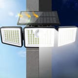 Lámpara en un pilar con flechas de sol sobre el panel y los LED encendidos de día y de noche.