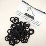Ligas negras para el cabello colocadas junto a una bolsa translúcida con cierre.