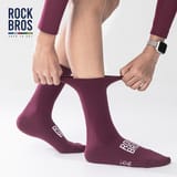 Manos que estiran el puño de un calcetín morado puesto en el pie para mostrar su elasticidad