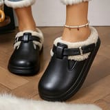 Pies calzados con los chodos negros sobre piso de madera, con jeans de dobladillo con pelo y tobillera de perlas.