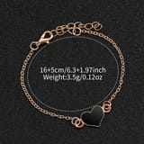 Pulsera dorada con dije de corazón negro sobre fondo oscuro con medidas y peso señalados.