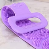 Detalle cercano de la agarradera y las cerdas cortas de silicona de una tira exfoliante morada.