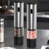 Par de molinillos eléctricos de acero inoxidable apoyados verticalmente sobre la mesada de cocina.