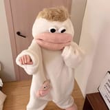 Persona con enterizo blanco de peluche y pelo rubio posando con el puño cerrado hacia adelante.