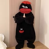 Persona de pie usando un pijama enterizo de felpa negra con labios rojos y cabello rojo.