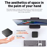 Mano abierta junto a la mini PC de tamaño compacto sobre un escritorio con monitor.